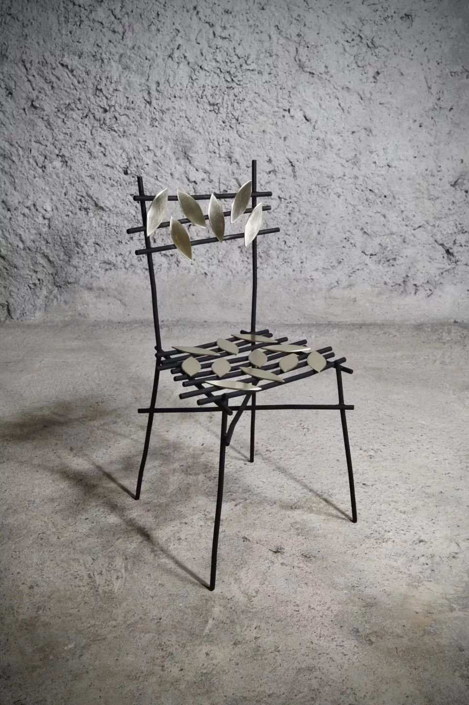 Chaise en acier noir, dossier semé de feuilles de laiton brossé, assise tressée à motif contrasté.