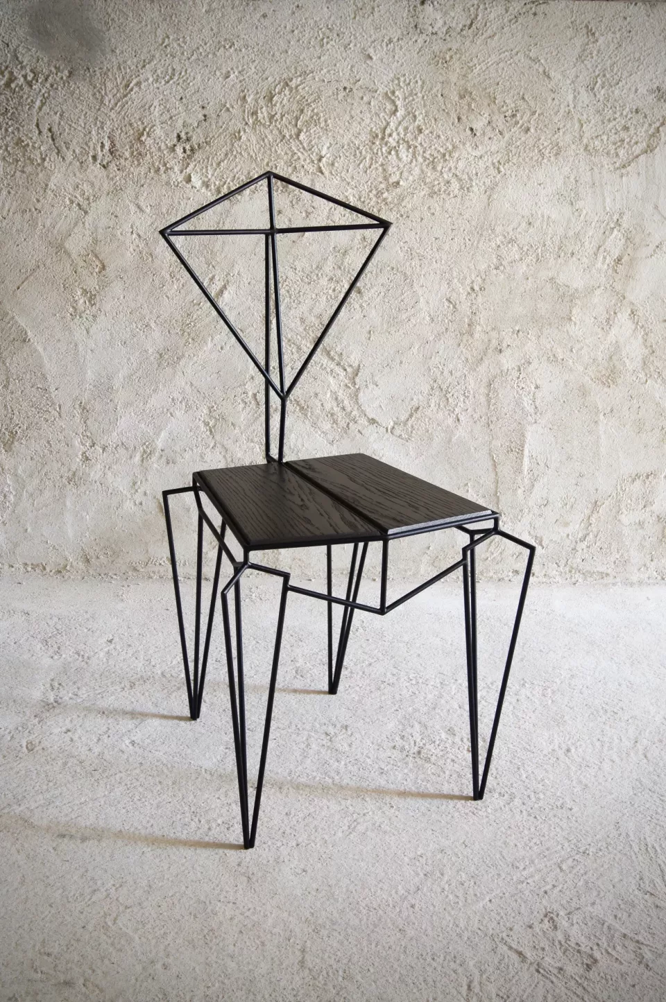 Chaise géométrique en acier noir filiforme, dossier en losange ouvert, assise de chêne teinté sombre.
