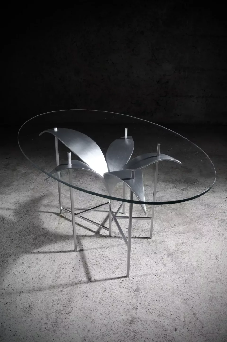 Table basse à plateau de verre ovale, piétement d’acier peint clair déployé en pétales et en tiges.