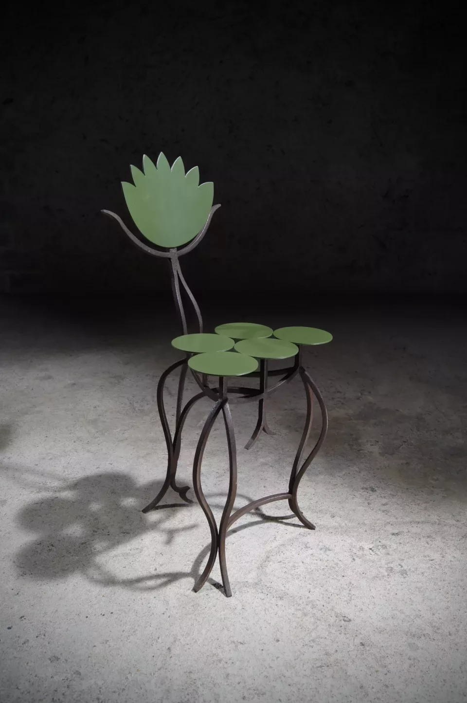 Guéridon aux feuilles de nénuphar vertes et fleur ouverte, piétement d’acier rouillé aux courbes végétales.