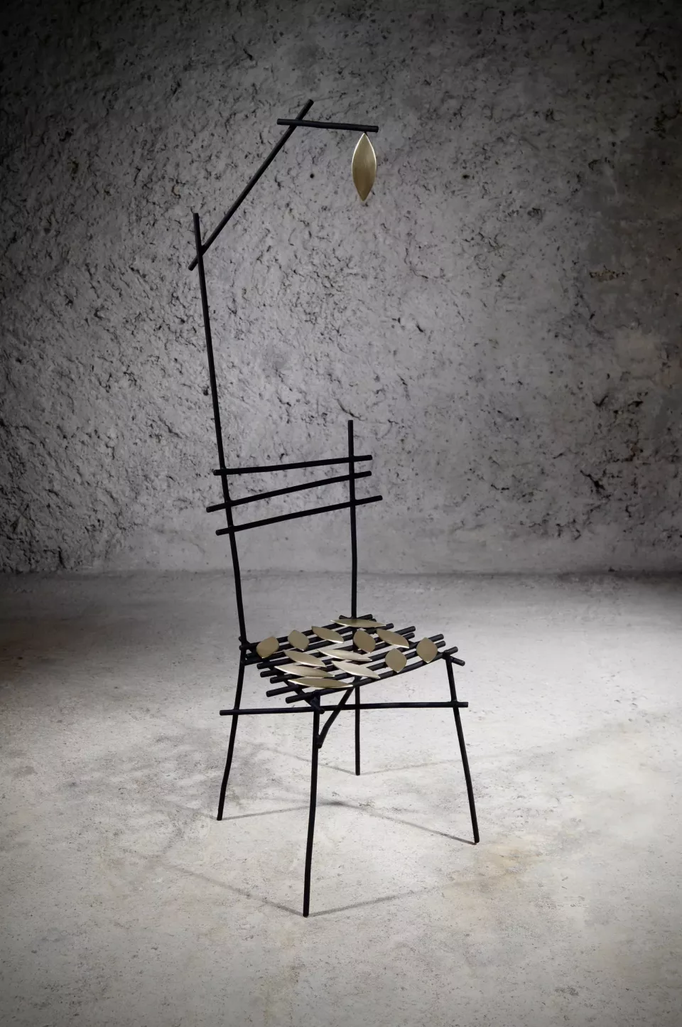 Chaise haute en acier noir au dossier élancé, tige portant une feuille de laiton au-dessus de l’assise tressée.